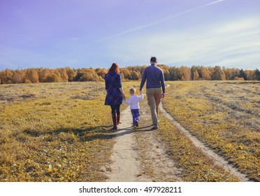 Family holding hands go on a field.