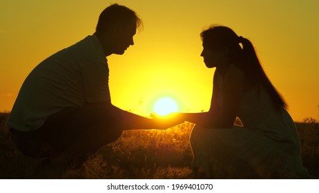 Family holding hands at sunset. Happy couple, family holding warm sun in their palms at sunset. Hold out your hand to friend. Concept of family values, a symbol of love, warmth, friendship, happiness.