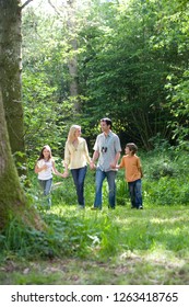 Family holding hands through forest on countryside walk