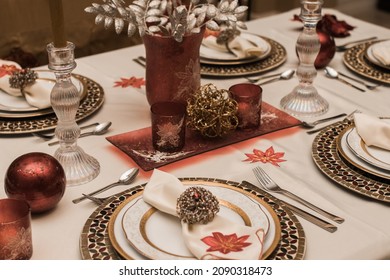 Family Holiday Festive Table Setup For Christmas Dinner. Gold And Red Decorations On The Dinning Room Table.