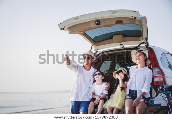 Family holiday\
lifestyle concept and summer vacation. Happy families is sitting in\
the back of the car. Parents and children are happy to play and\
laugh in the hot summer.