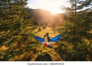 Family holiday on tourist trip. Children lie in tourist hammock in the forest on mountain landscape background. Top view, wide angle shooting. - Powered by Shutterstock