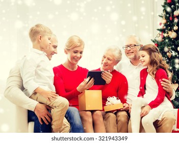 Family, Holidays, Christmas, Technology And People Concept - Smiling Family With Gift Box And Tablet Pc Computer Sitting On Couch At Home