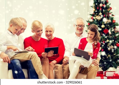 Family, Holidays, Christmas, Technology And People Concept - Smiling Family With Tablet Pc Computers Sitting On Couch At Home