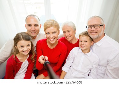 Family, Holidays, Generation, Christmas And People Concept - Smiling Family With Camera And Selfie Stick Taking Picture At Home