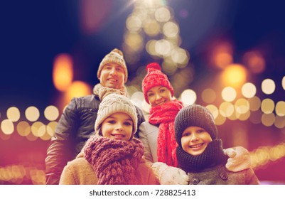 Family, Holidays And People Concept - Happy Parents With Kids Outdoors Over Christmas Lights Background