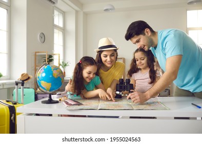 Family At Home Discussing Travel Route. Cheerful And Active Parents With Children Smiling Look At The Map, Deciding Where To Go On Vacation. Concept Of Active Recreation, Summer Holidays And Tourism.