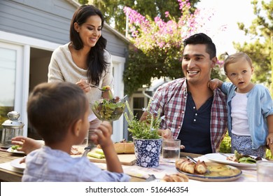 Family At Home Eating Outdoor Meal In Garden Together