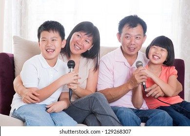 Family At Home. Portrait Of A Happy Asian Family Singing Karaoke Through Microphone In The Living Room