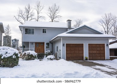 Family House With Front Yard And Driveway In Snow. Residential House On Winter Cloudy Day