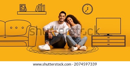 Family Housing. Happy Arab Couple Sitting On Floor Near Orange Wall With Drawn Interior, Smiling Young Spouses Imagining Their New Home, Planning Relocation In Empty Room, Hugging, Creative Collage