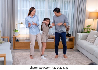 Family Husband Wife And Daughter Stand Happy Dancing Exercise Together On The Carpet In The Leaving Room