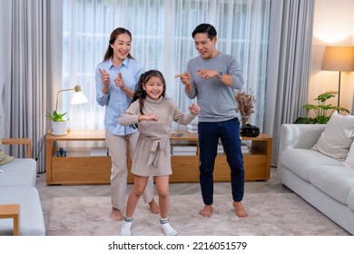 Family Husband Wife And Daughter Stand Happy Dancing Exercise Together On The Carpet In The Leaving Room