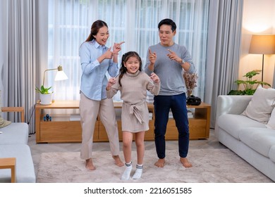 Family Husband Wife And Daughter Stand Happy Dancing Exercise Together On The Carpet In The Leaving Room