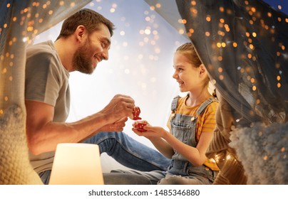 Family, Hygge And People Concept - Happy Father And Little Daughter Playing Tea Party In Kids Tent At Night At Home