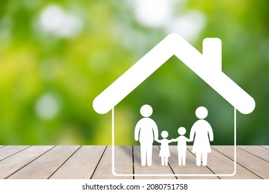 Family Icon And House Model Placed On Wooden Table And Green Background. Demonstrates The Love And Commitment Of Family Members.