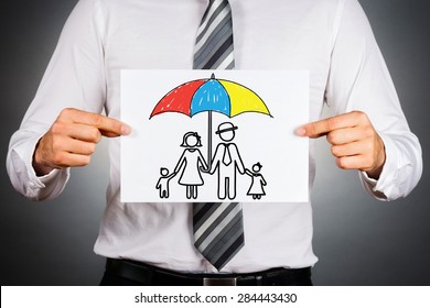 Family insurance concept. Businessman holding paper with drawing of a family under the umbrella.  - Powered by Shutterstock