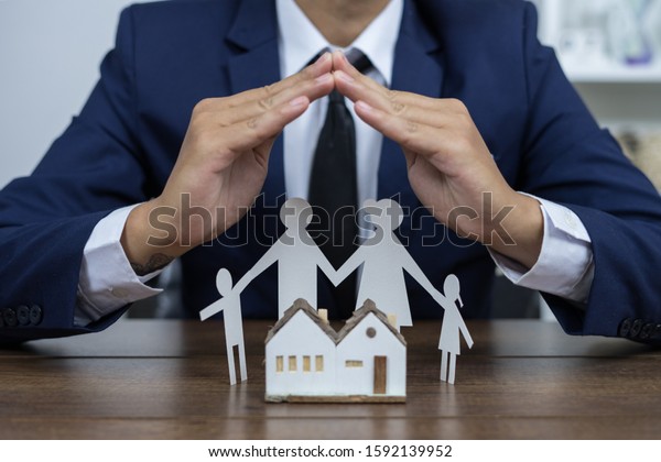Family insurance\
and home. Man in shirt covers his family with his father, mother,\
son and daughter and the\
house