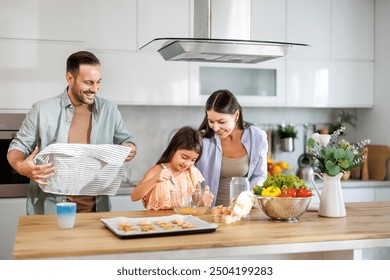 Family joyfully baking cookies with their young daughter in the kitchen. - Powered by Shutterstock