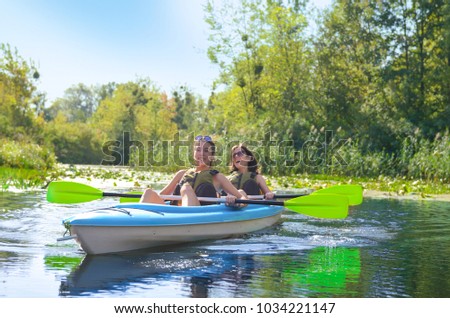 Family kayaking, mother and daughter paddling in kayak on river canoe tour having fun, active autumn weekend and vacation with children, fitness concept