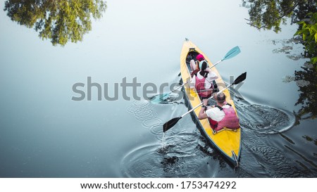 Family kayaking together in river.Tourists kayakers woman,man and child touring canoeing in a lake on a summer day.Back view.Summer family travel vacation concept. Active rest, water sports