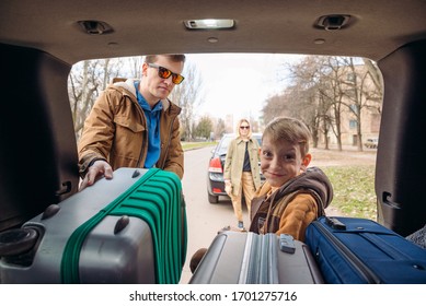 Family With Kid Putting Bag In Car Trunk