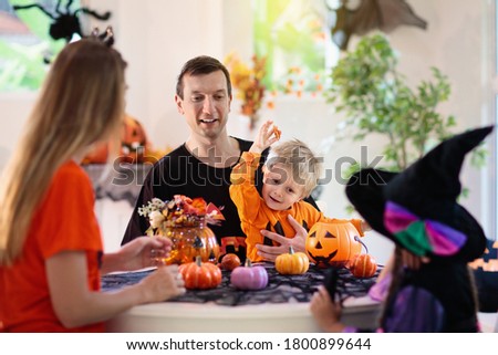 Family with kids carving pumpkin. Halloween trick or treat. Parents and kids decorating home. Children in witch costume and hat carve lantern. Autumn decoration. Boy and girl trick or treating.
