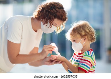 Family With Kids In Face Mask In Shopping Mall Or Airport. Mother And Child Wear Facemask During Coronavirus And Flu Outbreak. Virus And Illness Protection, Hand Sanitizer In Public Crowded Place.