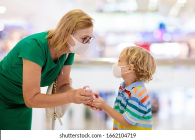 Family with kids in face mask in shopping mall or airport. Mother and child wear facemask during coronavirus and flu outbreak. Virus and illness protection, hand sanitizer in public crowded place.