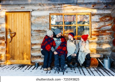 Family With Kids Outdoors On Beautiful Winter Day In Front Of Log Cabin Vacation House