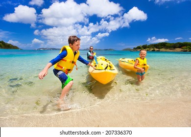 Family With Kids Paddling On Colorful Yellow Kayaks At Tropical Ocean Water During Summer Vacation