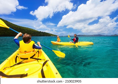 Family With Kids Paddling On Colorful Yellow Kayaks At Tropical Ocean Water During Summer Vacation