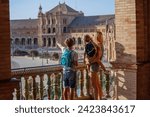 Family with kids in Sevilla overlook magnificent plaza de Espana in sunset light during their summer vacations in Spain