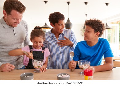 Family In Kitchen With Children Making And Eating Ice Cream Desserts