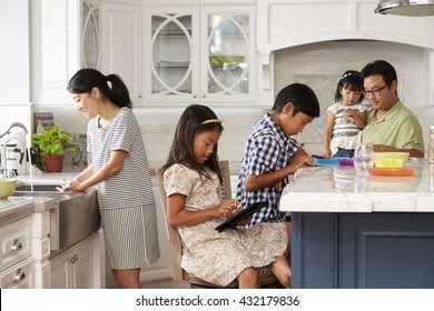 Family In Kitchen Doing Chores And Using Digital Devices - Powered by Shutterstock