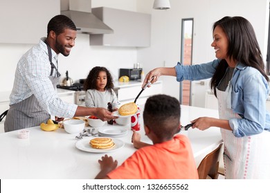 Family In Kitchen At Home Making Pancakes Together