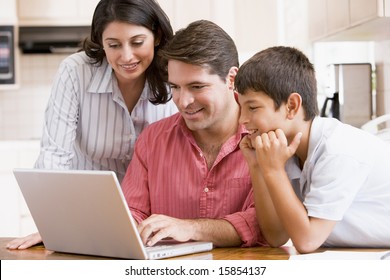 Family In Kitchen With Laptop Smiling