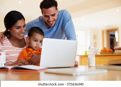 Family In Kitchen Looking At Laptop Together