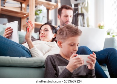 Family with laptop, tablet and smartphone at home, everyone using digital devices