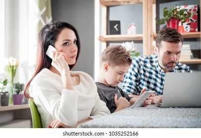 Family With Laptop, Tablet And Smartphone At Home, Everyone Using Digital Devices