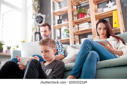 Family With Laptop, Tablet And Smartphone At Home, Everyone Using Digital Devices