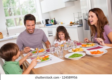 Family Laughing Around A Good Meal In Kitchen