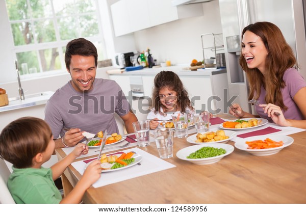 Family laughing\
around a good meal in\
kitchen