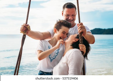 Family Laughing Siting On Swing Tropical Beach