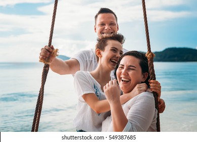 Family Laughing Siting On Swing Tropical Beach