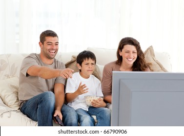 Family laughing while watching television together in the living-room