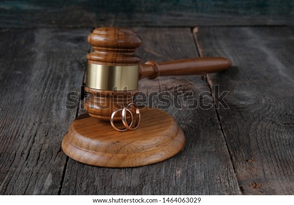 Family law concept, judge gavel and wedding\
rings on wooden\
background