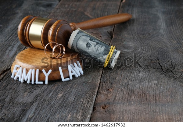 Family law concept, marriage\
contract, judge\'s gavel, wedding rings, text, money on wooden\
background.