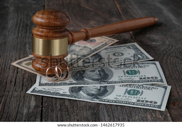 Family\
law concept, marriage contract, property section, judges gavel,\
wedding rings and money on a wooden\
background.