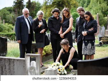 Family laying flowers on the grave - Shutterstock ID 1230694315